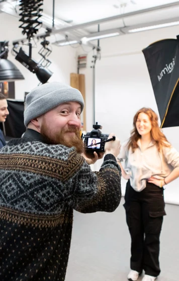 Student photographer capturing a portrait in a professional studio setup with lighting equipment. Student photographer capturing a portrait in a professional studio setup with lighting equipment.